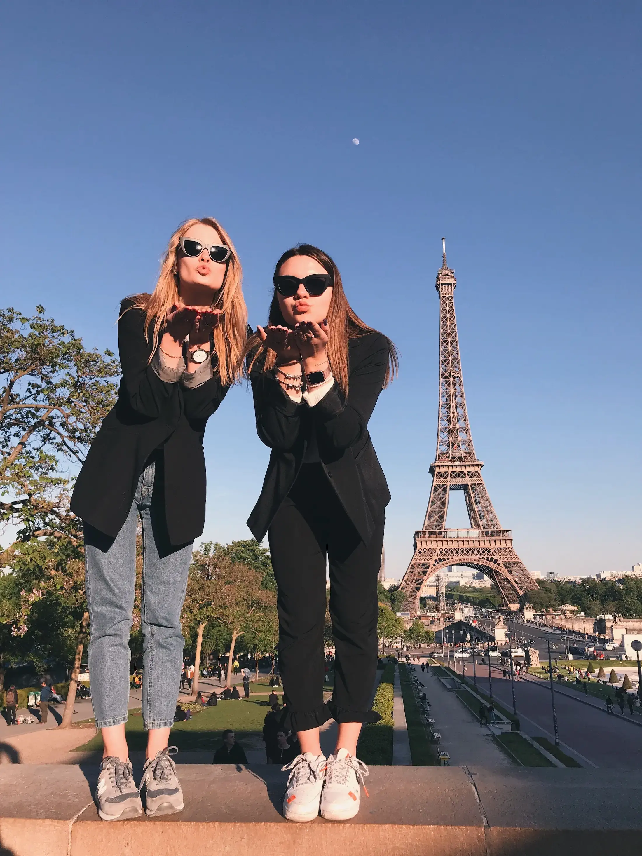 two women blowing kisses in front of Eiffel Tower