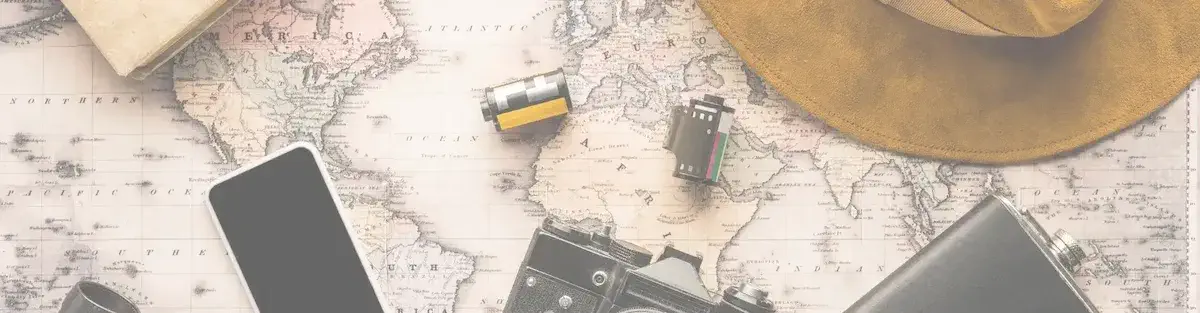 Essential travel gear flatlay on map with phone, hat, and camera